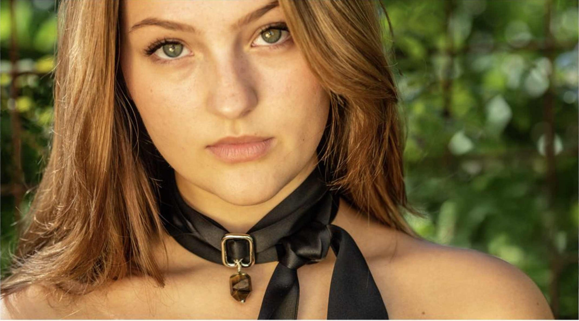 Woman wearing a Sadhana Beads black choker with a blurred green background